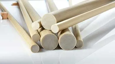 Close-up of light-colored polydowels of various diameters, piled on a reflective white surface.