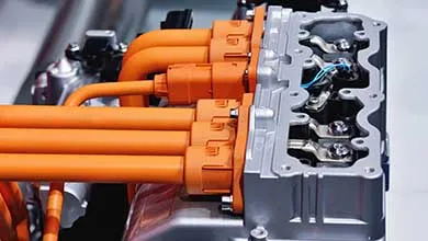 Thick, bright orange cables connect to a silver electric vehicle component.