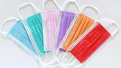 Assortment of disposable face masks in multiple colors arranged in a fan shape on a white background.