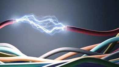 Exposed electrical wires with visible electric arc between two cable ends against a dark background.