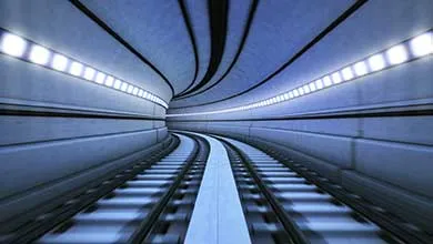First-person view speeding along curved train tracks inside a modern tunnel illuminated with blue lights.
